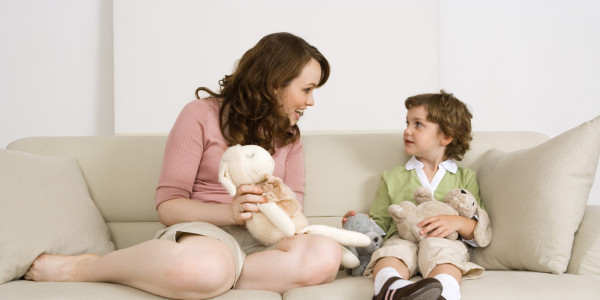 Mother and daughter sitting on sofa with stuffed animals